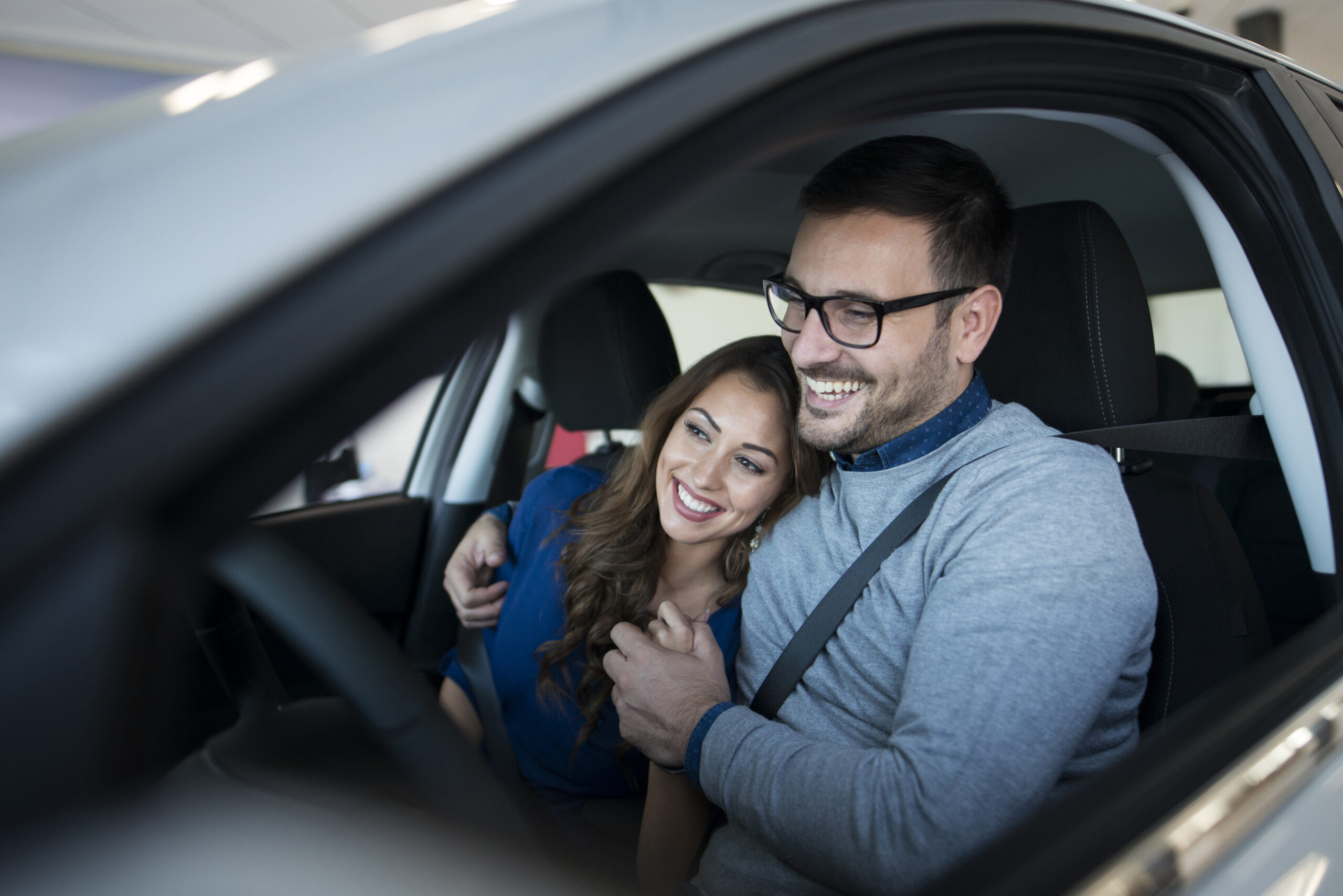 Happy young couple enjoying their brand new car.